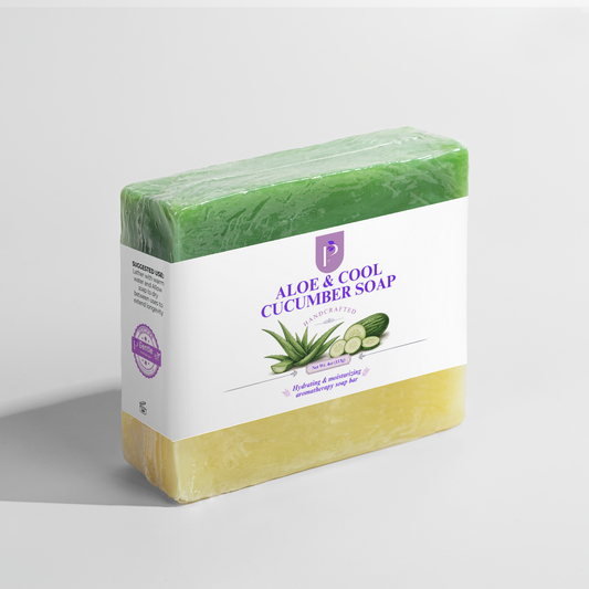 A bar of Aloe & Cool Cucumber Soap wrapped in clear plastic with a white paper label, shown on a light gray background. The soap has a green top half and a pale yellow bottom half, with the label featuring purple text and illustrations of aloe vera and cucumber.