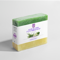 A bar of Aloe & Cool Cucumber Soap wrapped in clear plastic with a white paper label, shown on a light gray background. The soap has a green top half and a pale yellow bottom half, with the label featuring purple text and illustrations of aloe vera and cucumber.