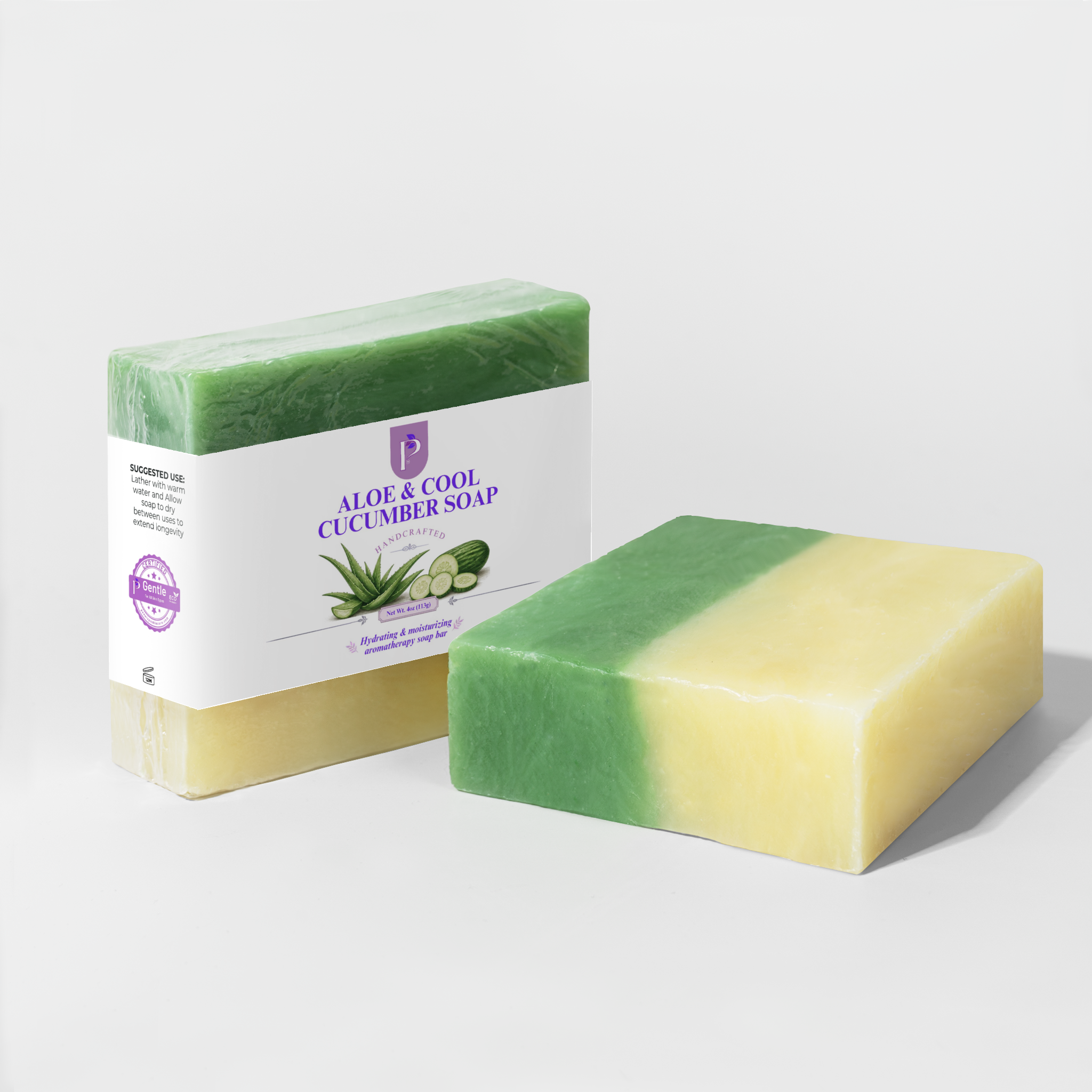 A bar of Aloe & Cool Cucumber Soap shown both wrapped in a white paper sleeve and unwrapped, revealing a dual-tone green and pale yellow color. The soap bar in the foreground is set against a clean, light gray studio background.