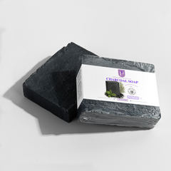 A bar of charcoal soap shown unwrapped next to its wrapped package, on a clean white background with a soft shadow.
