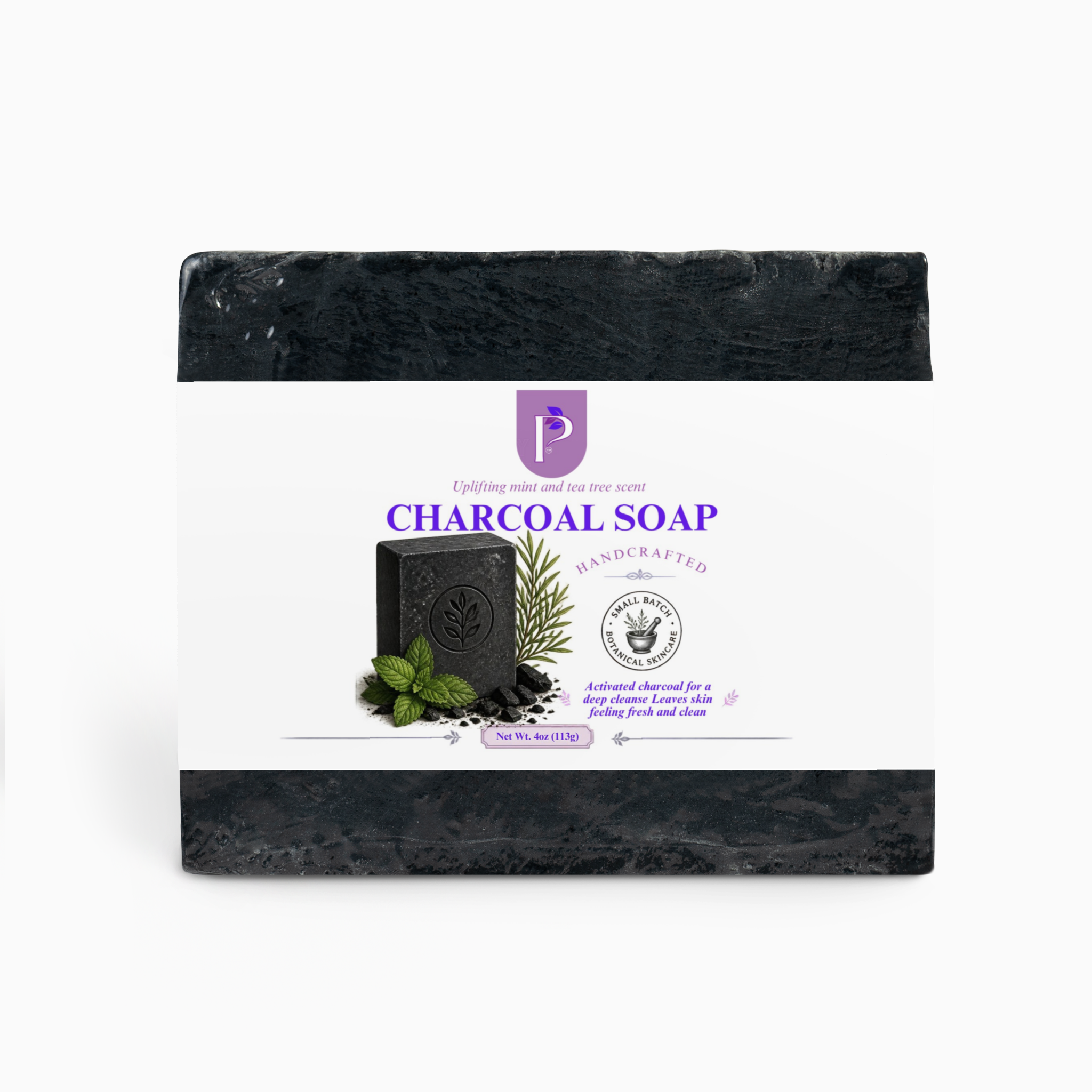 A packaged bar of charcoal soap centered on a light gray background. The soap is wrapped in a white paper label with purple text reading 'CHARCOAL SOAP' and a small product photo of a dark soap bar with mint leaves and a rosemary sprig.