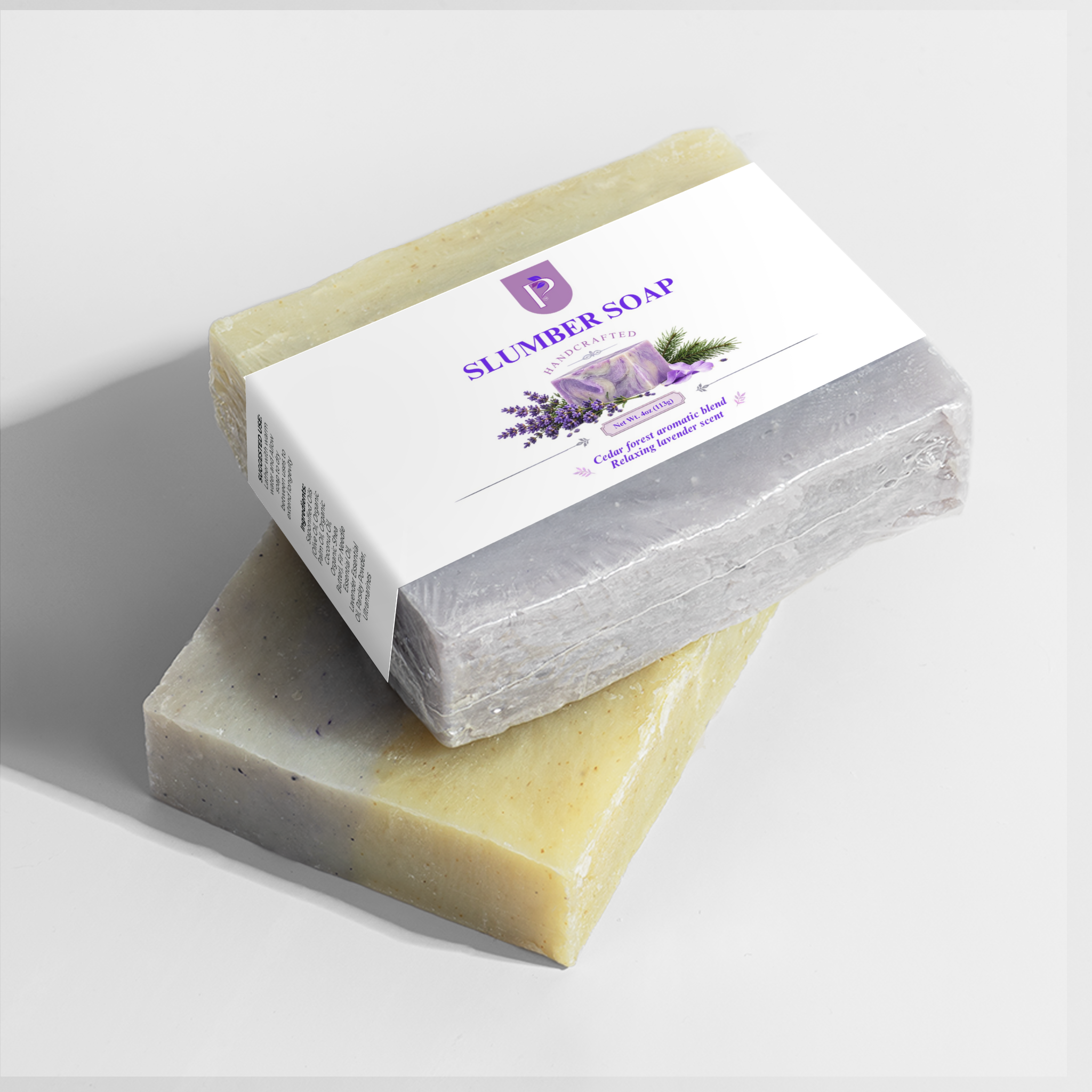 Two rectangular bars of soap stacked on a light gray background. The top bar is wrapped in a clear plastic sleeve with a white paper label reading 'SLUMBER SOAP' and 'Lavender & Vanilla'; the bottom bar is unwrapped, showing a pale yellow-green marbled soap bar with lavender flecks.