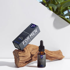 A bottle of PUNTS FOR MEN Maintain 17% Strength Nicotine Salve next to its black packaging box, styled on a piece of natural driftwood with a white background and a green plant in the corner.