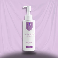 A white pump bottle of Purifying Blemish Cleanser with a purple logo and text, set against a draped lavender fabric background.