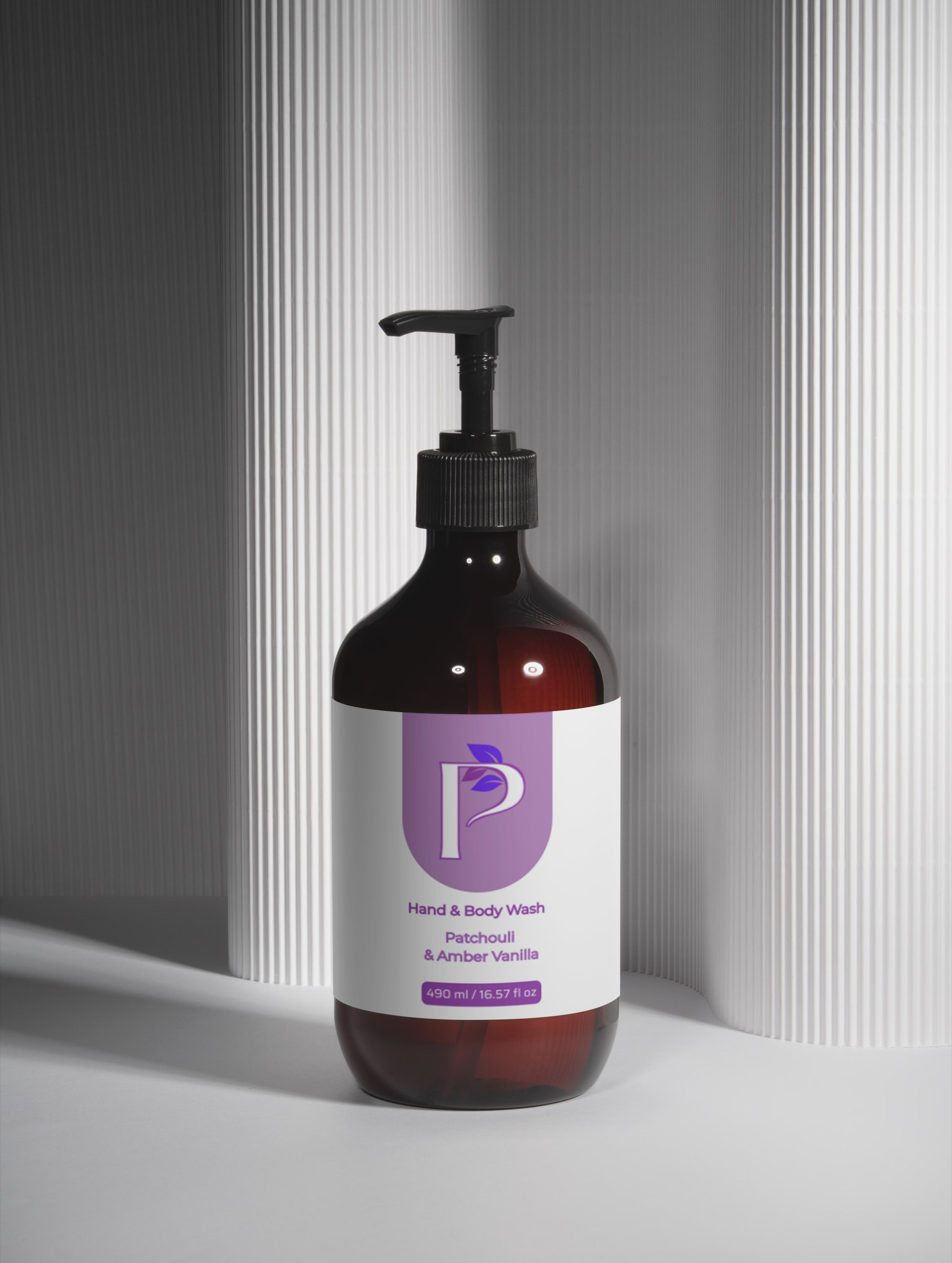 An amber glass pump bottle of hand and body wash with a black dispenser and a white label featuring a purple logo, set against a gray background with vertical ribbed panels.