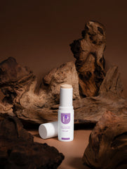 Two skincare bottles on a wooden surface with a brown background