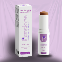 A cosmetic color correcting ceramide stick shown next to its retail box. The stick has a white body with a light brown/tan cosmetic product visible at the top, and the box and label feature purple branding and text.