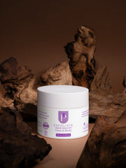 A white jar of Keratin Intensive Repair Hair Mask by Purify Cosmetics, styled on a beige surface surrounded by rustic driftwood pieces against a dark brown background.