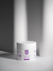 A white cosmetic jar labeled 'P Exfoliate Exfoliating Mask Face & Body' placed on a light gray surface with vertical ribbed panels in the background.