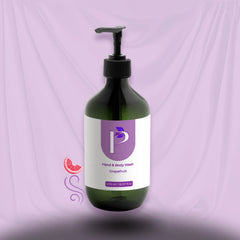 A dark green pump bottle of grapefruit hand and body wash with a white and purple label, set against a draped lavender background.
