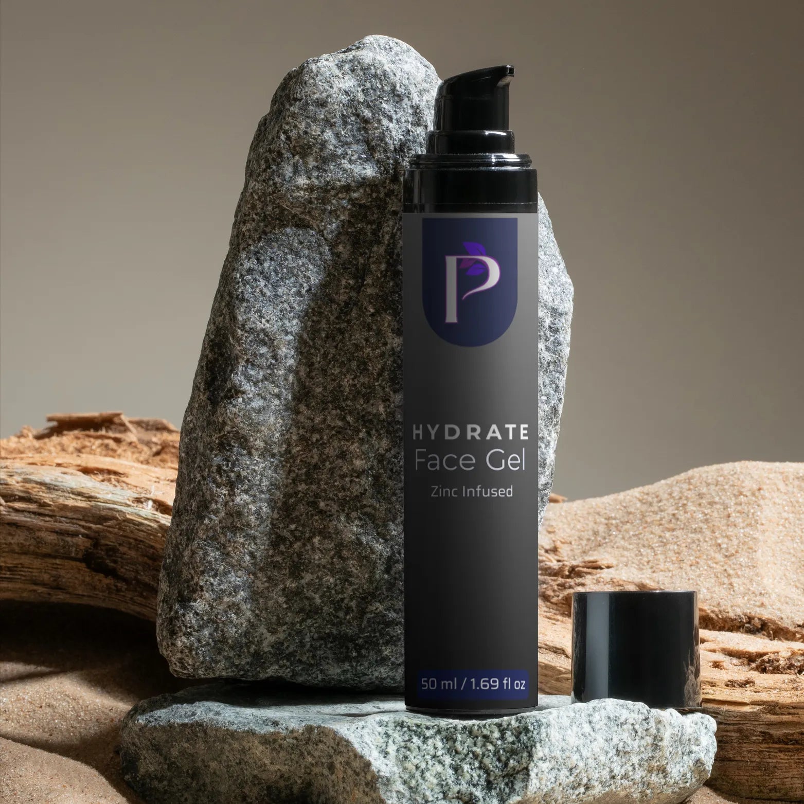 A black pump bottle of Hydrate Face Gel stands on a stone surface with a large gray rock behind it and a small detached cap beside the bottle. The bottle label shows a purple circular logo with a white letter P and white text reading 'HYDRATE Face Gel' and 'Zinc Infused.