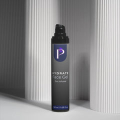 A single bottle of P hydra te Face Gel stands upright on a white surface between two gray ribbed columns. The bottle is dark gray with a black pump cap and a blue-purple logo panel on the front.
