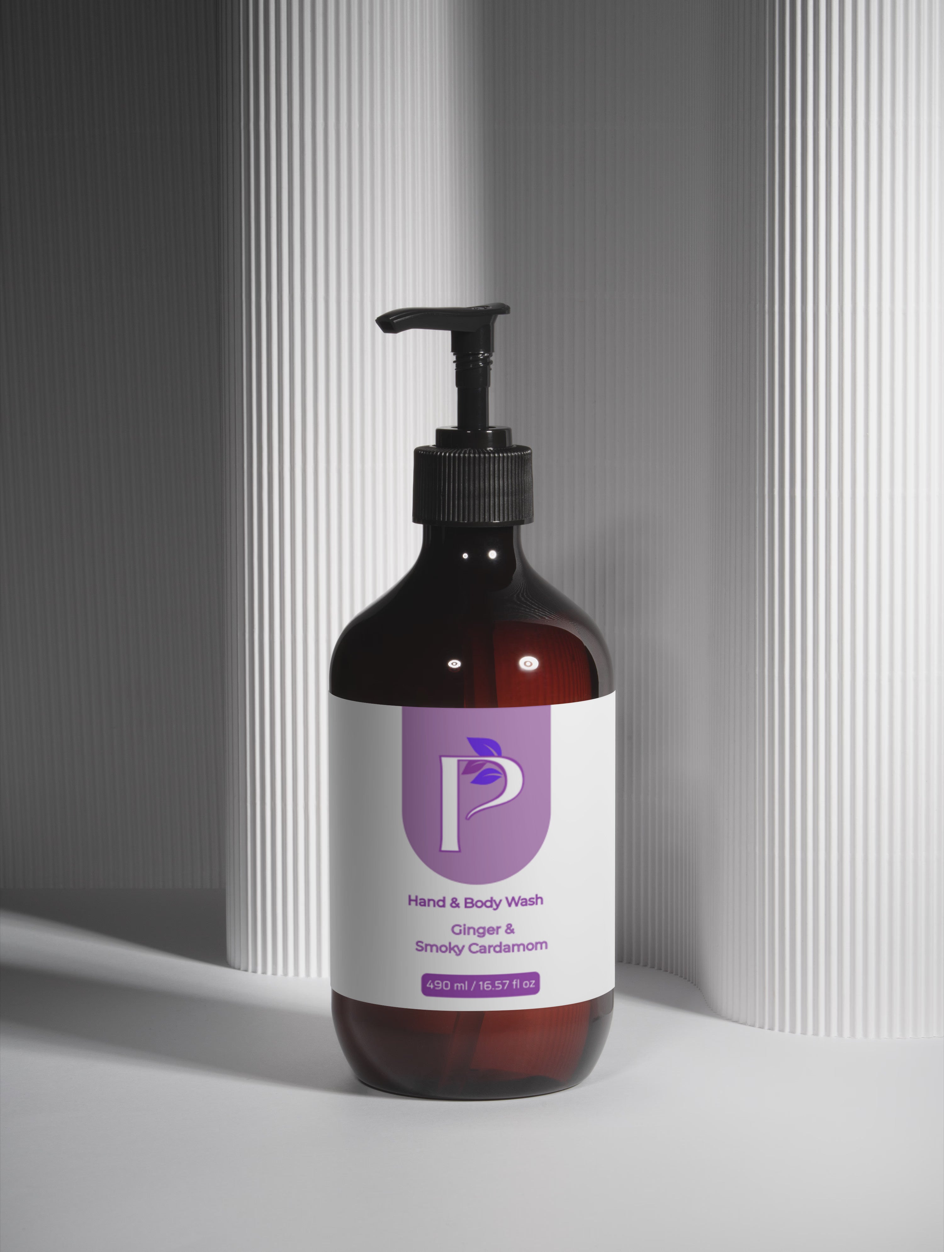 An amber glass pump bottle of hand and body wash with a black dispenser and a white label featuring a purple logo, set against a gray background with vertical ribbed panels.