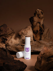Two skincare bottles on a wooden surface with a brown background
