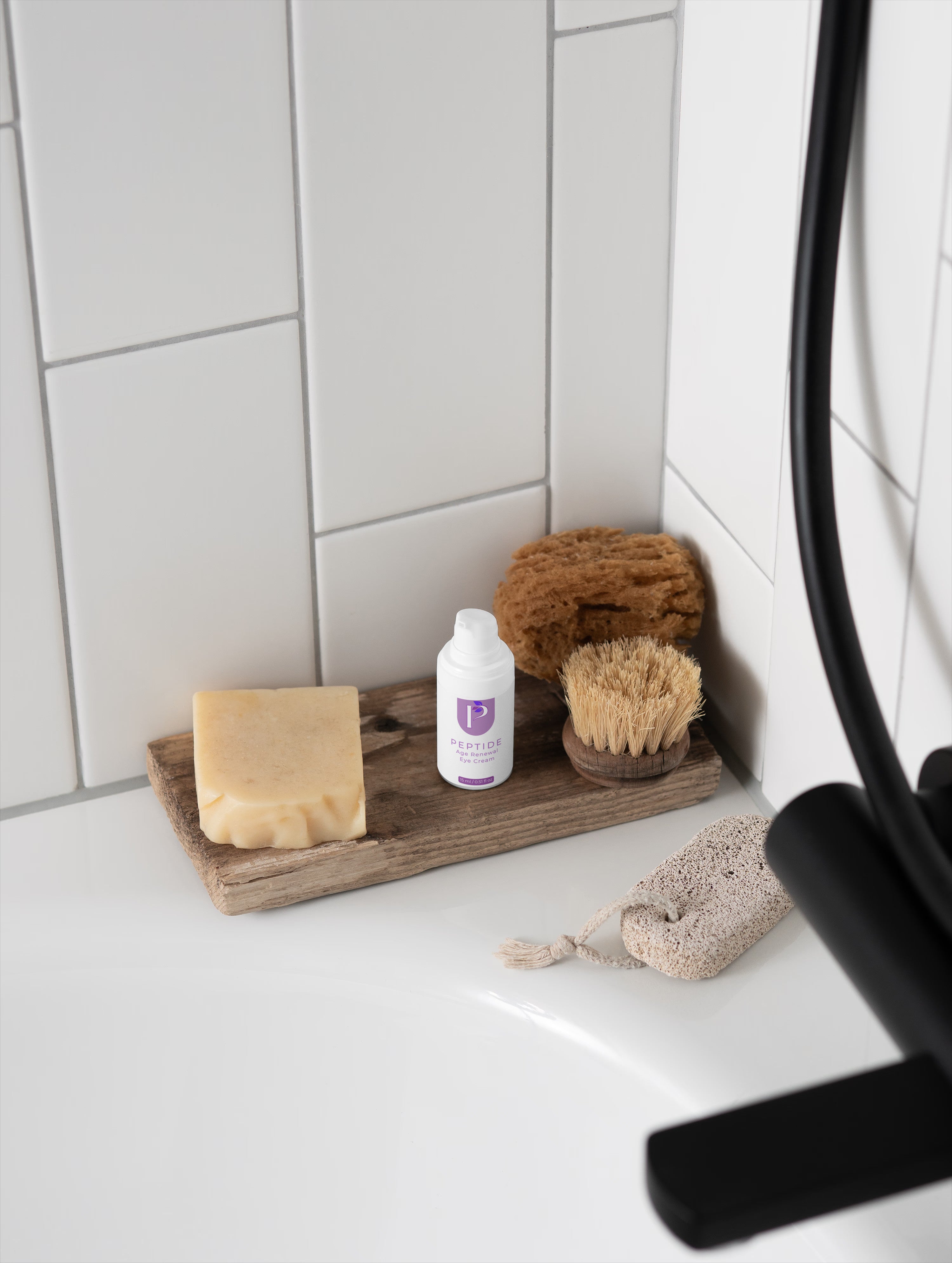 Bathroom corner with soap, bottle, and scrubber on a wooden tray against a tiled wall.