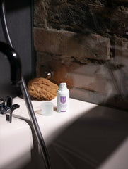 Bottle of lotion on a bathroom counter with a stone wall background